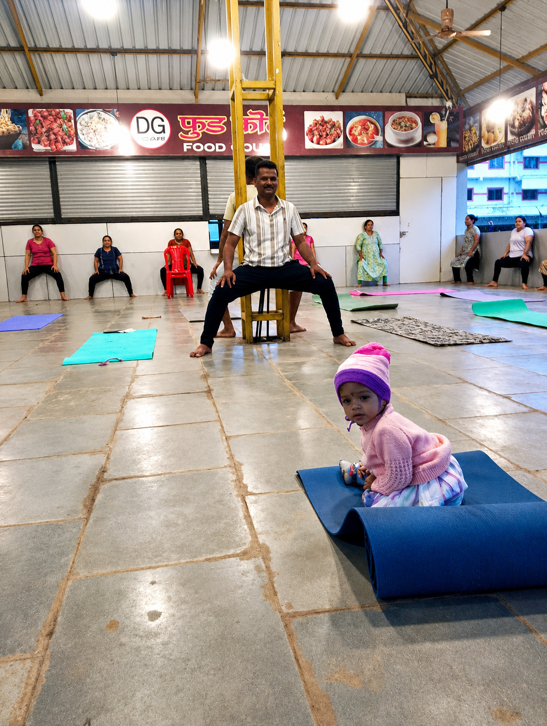 Instructor assisting a student with an inversion pose, indoor hall