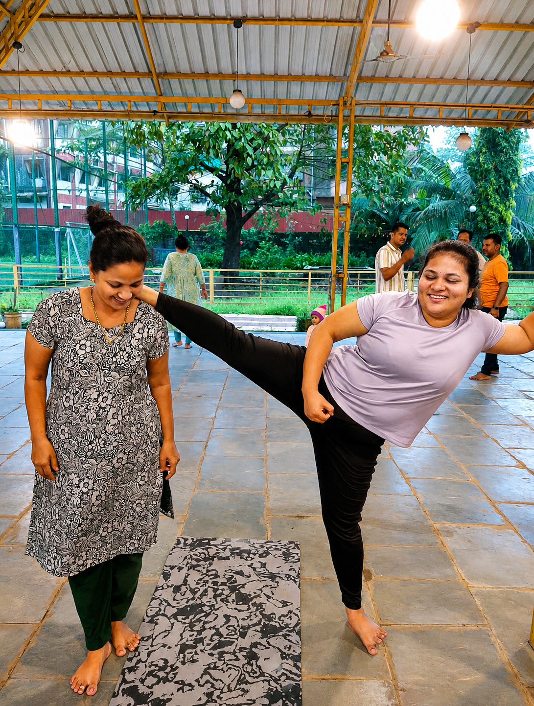 Instructor assisting a student in a standing balance pose outdoors