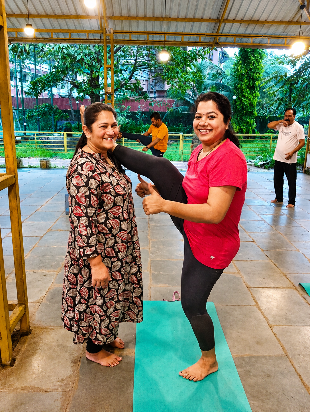 Instructor assisting a student in a standing pose indoors