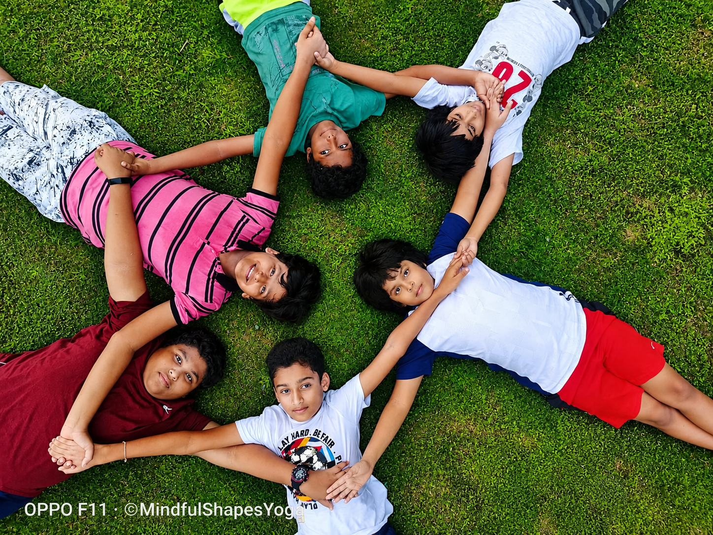 Children's yoga class lying in a circle on the grass