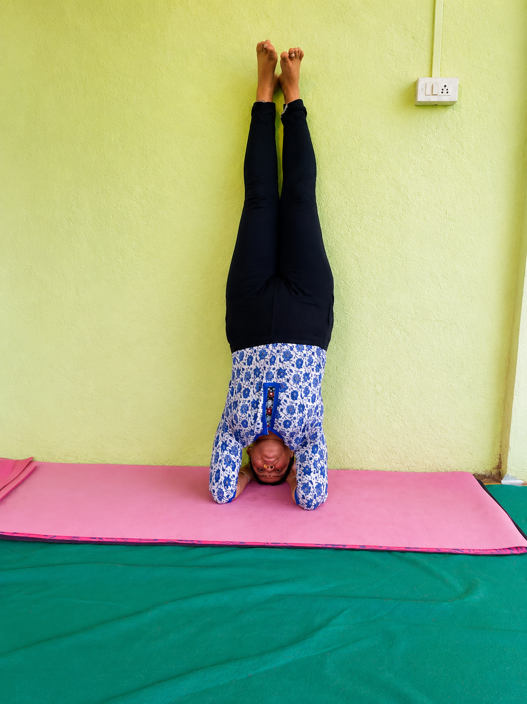 Student practicing headstand against the wall