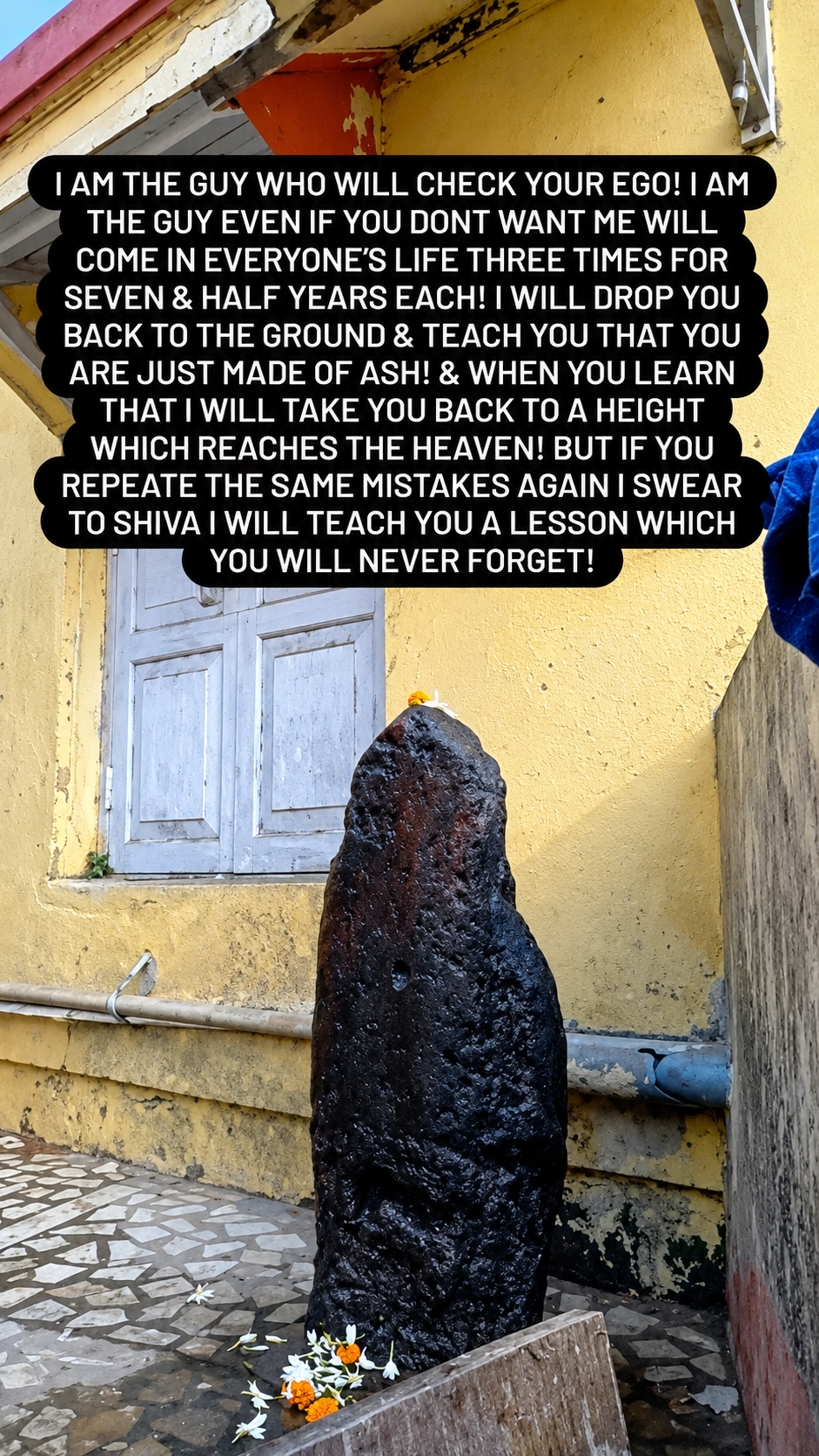 Dark stone deity idol at an outdoor shrine